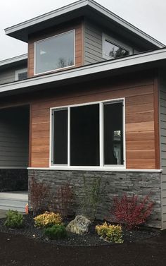 a house that has some plants in front of it and two windows on the side