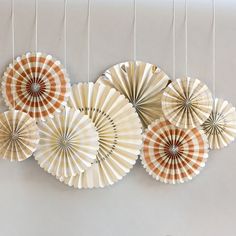 four paper fans hanging from strings on the wall