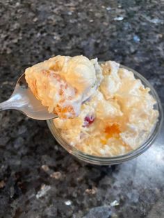 a spoon full of food sitting on top of a counter next to a glass bowl