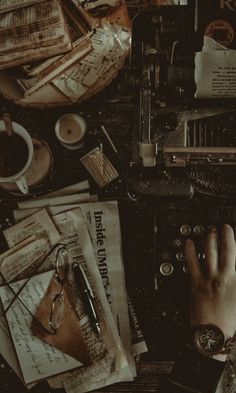 a person typing on a typewriter surrounded by old papers and other items that are scattered around