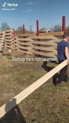 a man is holding a large piece of wood in his hand while standing next to a fence