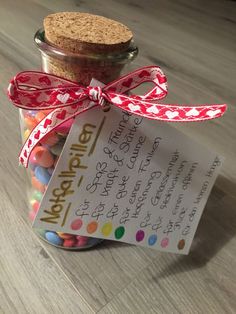 a jar filled with lots of colorful candies and a note attached to the lid