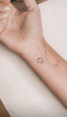 a person's arm with a small heart tattoo on the left side of their wrist