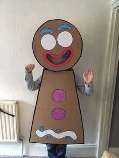 a young boy holding up a cardboard ginger costume