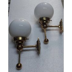 two brass and glass wall lights on a white tableclothed surface, with one light turned off to the side