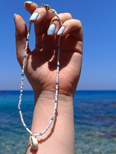 Natural cowrie shell necklace, Greek aesthetic necklace, White seed beaded choker, Light blue crystal beaded necklace, Summer beach pendant ☙ Greek aesthetic necklace with white seed beads, light blue crystal beads and a charm natural cowrie shell with a light blue swarovski on. The perfect necklace to add some summer Greek vibes to your outfit. You can mix and match it with similar aesthetic necklaces from my collection. Try to offer it as a gift to your friends that love Greece and blue details. ❧ Details : ❥ The necklace has extended chain to fit up to 5 cm ≈ 2 inches length Materials : ❥ The cowrie shell is natural ❥ The necklace is based on a silver steel wire combined with white seed beads and light blue crystal beads ❥ The chain is made out from stainless steel  ❥ The connecting hoo Summer Beach Beaded Necklaces With Spacer Beads, Summer Beach Beaded Necklace With Spacer Beads, Summer Spacer Bead Choker Jewelry, Dainty White Beaded Necklace For Festivals, Beach Choker With Round Beads, Beaded Choker With Round Beads For Beach, Beaded Choker For The Beach, Handmade White Crystal Choker Necklace, White Ocean-inspired Jewelry With Round Beads