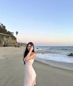 a woman is standing on the beach talking on her cell phone