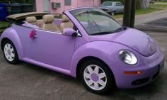 a purple convertible car parked in front of a pink house with a bow on the top