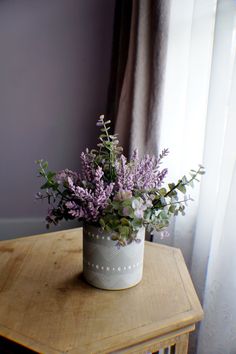 a bouquet of flowers sitting on top of a wooden table next to a curtained window