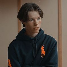 a young man in a blue hoodie with an orange polo logo on his shirt