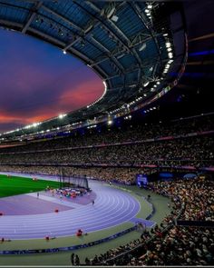 a stadium filled with lots of people sitting on top of a green and white field