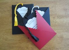 two black and red envelopes with tassels on them sitting on a wooden table