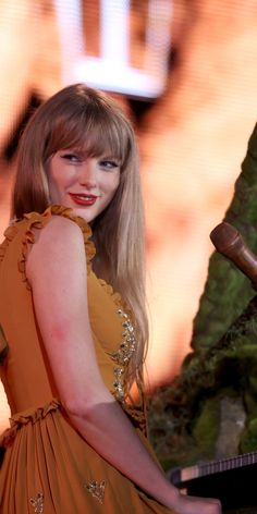 a woman with long blonde hair wearing an orange dress