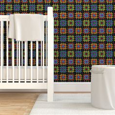 a white crib in front of a wallpapered nursery room with a blue and green pattern