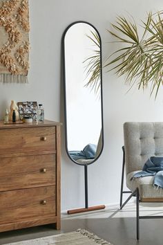 a living room with a chair, mirror and plant