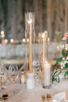 the table is set with candles, flowers and wine glasses for an elegant wedding reception