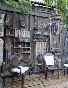 two chairs sitting on top of a wooden floor next to a wall covered in pots and pans