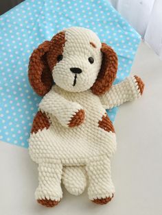 a white and brown dog stuffed animal sitting on top of a blue polka dot cloth