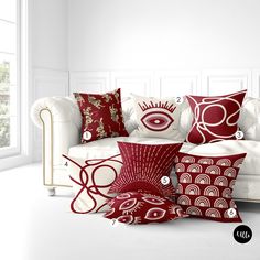 a white couch sitting next to a window with red pillows on top of it's sides