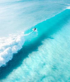 a man riding a wave on top of a surfboard in the ocean with blue water