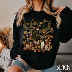 "With this Oversized Vintage Botanical Wild Flower crewneck sweatshirt - a seamless blend of classic comfort. It's not just a shirt; it's a wearable garden, a celebration of nature's beauty in every petal and leaf. Fall in love with the timeless appeal of wild flowers as you step into this botanical masterpiece. Unisex Heavy Blend™ Crewneck Sweatshirt- Vintage Pressed Flowers Autumn/Fall Print Design Cottagecore Sweater Main Store: https://www.etsy.com/shop/May5thDesign?ref=seller-platform-mcnav For this Design on a T-SHIRT:  https://www.etsy.com/listing/1644687307/floral-cottage-core-shirt-comfort-colors?click_key=b4cd4405eabbd162d1fc3b3d7119c2fc20e64c50%3A1644687307&click_sum=1166090e&ref=shop_home_active_1&pro=1&sts=1 This sweatshirt offers the perfect blend of softness and warmth. Its Casual Long Sleeve T-shirt With Plant Print, Floral Print Long Sleeve Sweatshirt For Fall, Fall Floral Print Crew Neck Sweater, Casual Fall Tops With Plant Print, Black Long Sleeve Sweater With Floral Print, Floral Print Crew Neck Sweater For Fall, Oversized Floral Print Winter Tops, Oversized Floral Print Crew Neck Top, Oversized Floral Print Top For Winter