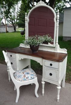 an antique vanity with mirror, stool and potted plant on it in front of a house