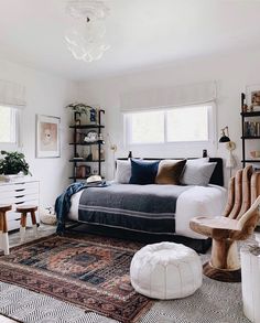 a bedroom with a bed, rug and two chairs in it's center area