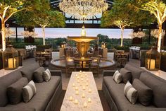 an outdoor seating area with chandeliers and candles on the tables in front of it