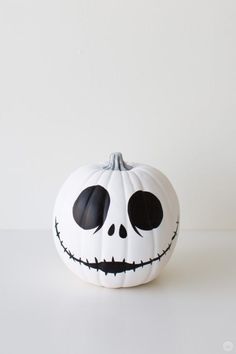 a white pumpkin decorated with black eyes and a jack - o'- lantern face