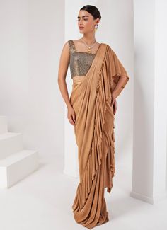 This elegant Gold Pre-Draped Lycra Saree Set, crafted from a luxurious blend of lycra and crepe, exudes timeless sophistication. The fluid draping of the gold saree, enhanced by the rich texture of the fabrics, makes it a standout choice for any special occasion. Paired with a striking grey blouse, intricately hand-embellished to add a touch of glamour, this ensemble is perfect for festive celebrations or sangeet ceremonies. Composition : Blouse - Crepe blend & Saree - Crushed Lycra Saree Care: Dry Clean Only and Vacuum Storage This product can be customized for sleeves, blouse length and neckline Delivery : 2-4 weeks as the product is hand crafted. Check Size Guide or choose MySize for free customisation (All Sizes above XL can be made at 15% additional cost) For more information and size Pre-draped Fitted Saree With Dupatta, Fitted Draped Lehenga With Cutdana, Fitted Pre-draped Party Wear Saree, Designer Pre-draped Fitted Saree, Pre-draped Traditional Sets For Reception, Pre-draped Sets For Reception With Traditional Drape, Festive Pre-draped Fitted Sets, Pre-draped Georgette Lehenga, Fitted Georgette Lehenga In Pre-draped Style