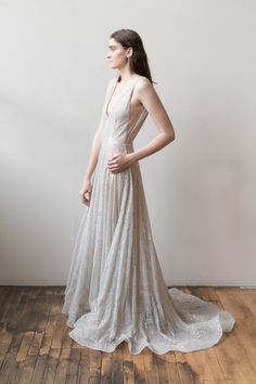 a woman in a white dress stands on a wooden floor and looks off to the side