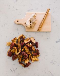 a cutting board topped with dried fruit next to a pile of sliced up ginger sticks