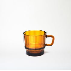 a yellow glass cup sitting on top of a white table