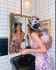 a woman in a zebra print dress is looking at her reflection in the bathroom mirror