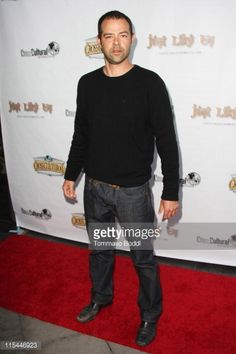 a man in black shirt and jeans standing on red carpet