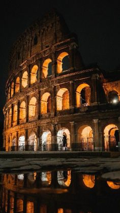 the colossion is lit up at night with its lights on and reflecting in the water