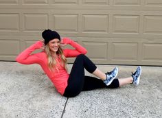 a woman sitting on the ground with her hands behind her head and wearing a beanie