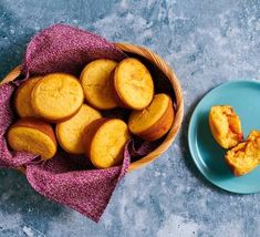 some food is on a blue plate and next to a basket full of muffins