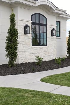 a white house with black windows and landscaping