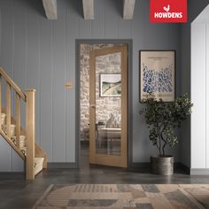 an open door leading to a living room with stone walls and wooden stairs, next to a potted plant