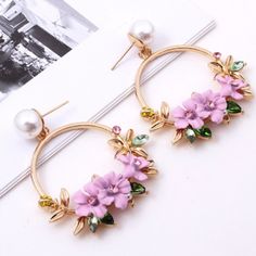 a pair of earrings with flowers and pearls