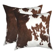 two brown and white cowhide pillows sitting on top of each other in front of a white background