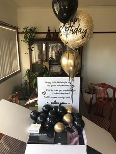 a table with balloons and a sign on it that says happy birthday to all of us