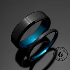 two wedding bands with blue and black inlays are sitting next to each other