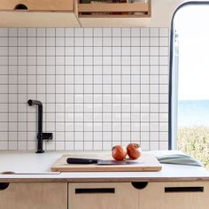 two onions sitting on top of a cutting board next to an open window in a kitchen