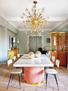 a dining room table with chairs and a chandelier hanging from it's ceiling