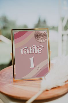 a table with a sign that says table 1 on it and a white feather sitting next to it