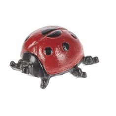 a red ladybug figurine sitting on top of a white surface with black spots