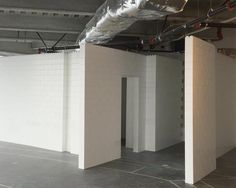 an empty room with white walls and exposed pipes