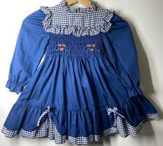 "Polly Flinders prairie toddler dress. Hand smocked and floral embroidered bodice.Labeled sz 4 (toddler) -measures pit to pit 10\" A small amount of stretch available / waist (elastic back) 10\"-10 1/2\"/ Ruffle bottom trim / length (shoulder to bottom) 21\"/ gingham trimmed bottom dust ruffle / full skirt & pull back bow sash / smoke free environment. (86)" Vintage Style Smocked Dress For Spring, Spring Vintage Smocked Dress With Smocked Bodice, Vintage Long-sleeved Smock Dress, Vintage Long Sleeve Smock Dress, Vintage Smocked Ruffle Dress For Summer, Vintage Smocked Summer Dress With Ruffles, Vintage Spring Dresses With Smocked Cuffs, Vintage Dresses With Smocked Cuffs For Spring, Spring Vintage Dresses With Smocked Cuffs